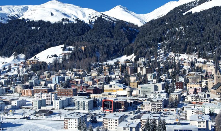 On a bright winter day, Davos, Switzerland can be seen from above, with a snowy landscape and the Schtzalp mountain in the distance.