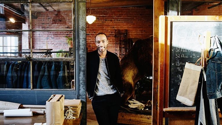 Young business professional leaning in a doorway.
