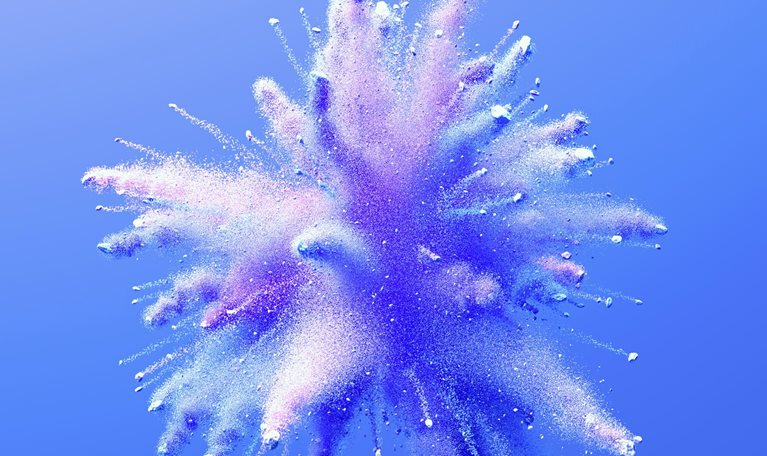 A vibrant burst of fine powder in shades of blue and purple explodes outward against a soft blue background. The particles radiate in all directions, creating a dynamic, cloud-like shape.