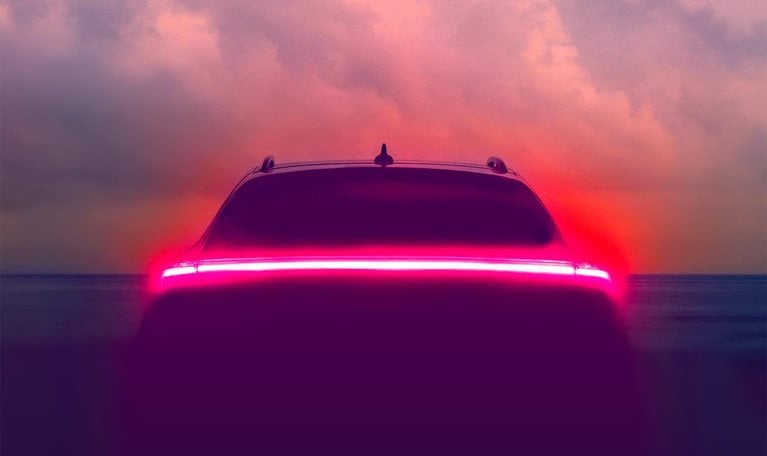Brake lights glowing on an autonomous vehicle with a hazy blue sky in the background