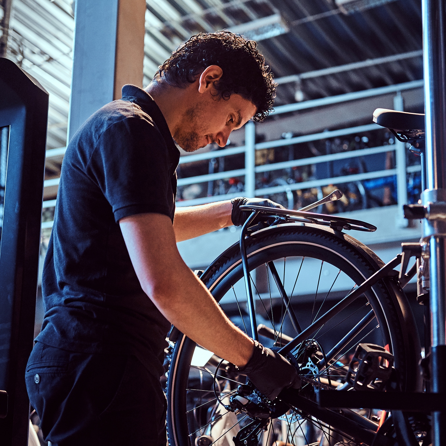 Attractive mechanic is fixing customer's bicycle at his own workshop.