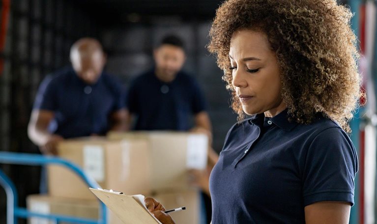 Woman supervising the shipping of cargo at a distribution warehouse stock photo