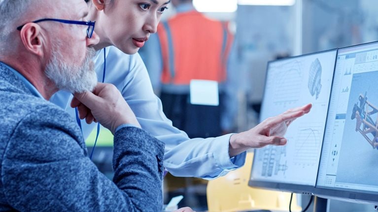 Asian female technician discusses work with middle aged designer.