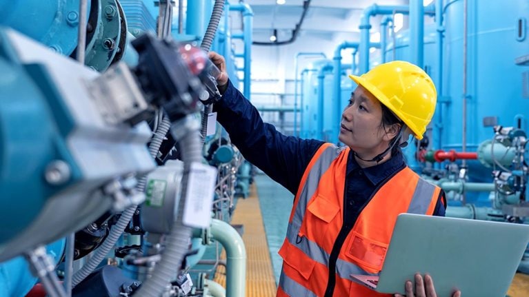 A female engineer works in a chemical plant using a laptop computer - stock photo