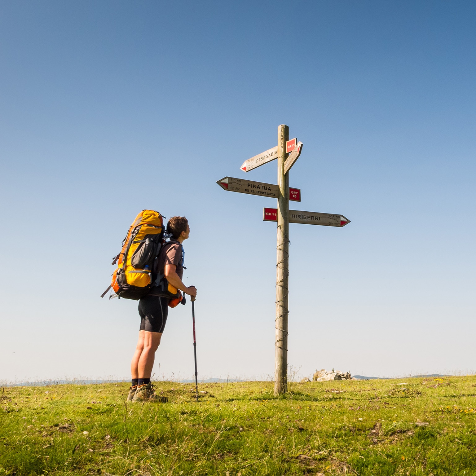 Hiker with backpack along trail looking a sign post at Sierra de Abodi in Navarra, Spain. - stock photo