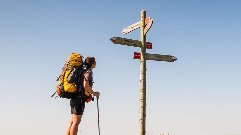 Hiker with backpack along trail looking a sign post at Sierra de Abodi in Navarra, Spain. - stock photo