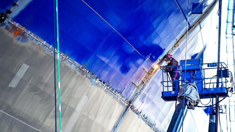 Low angle view of worker welding ship at industry
