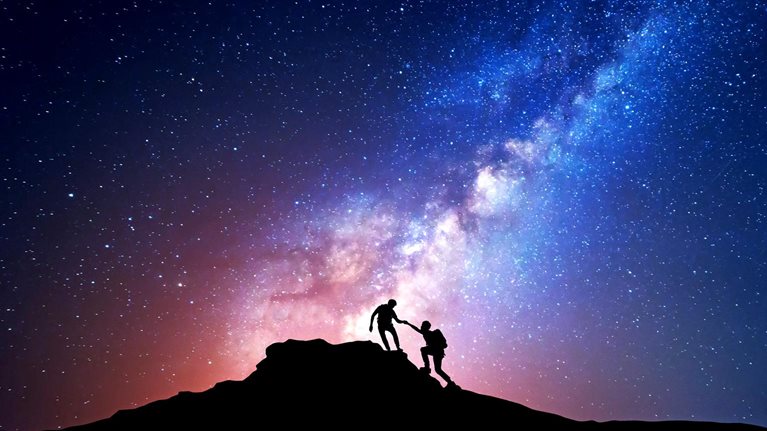 Silhouette of people climbing mountain at night