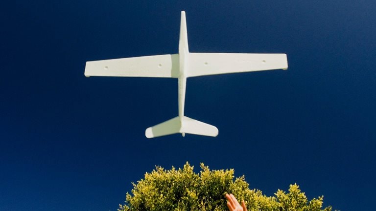 photo girl with outstretched arm as model plane flies above
