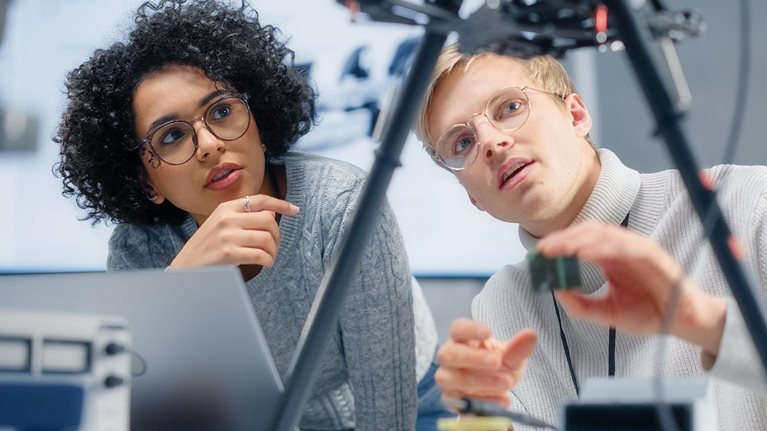 Two diverse developers brainstorming and programming, working together on a new drone.