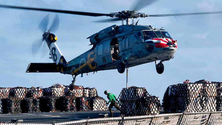 An MH-60S Sea Hawk helicopter lifts cargo from the fast combat support ship USNS Rainier