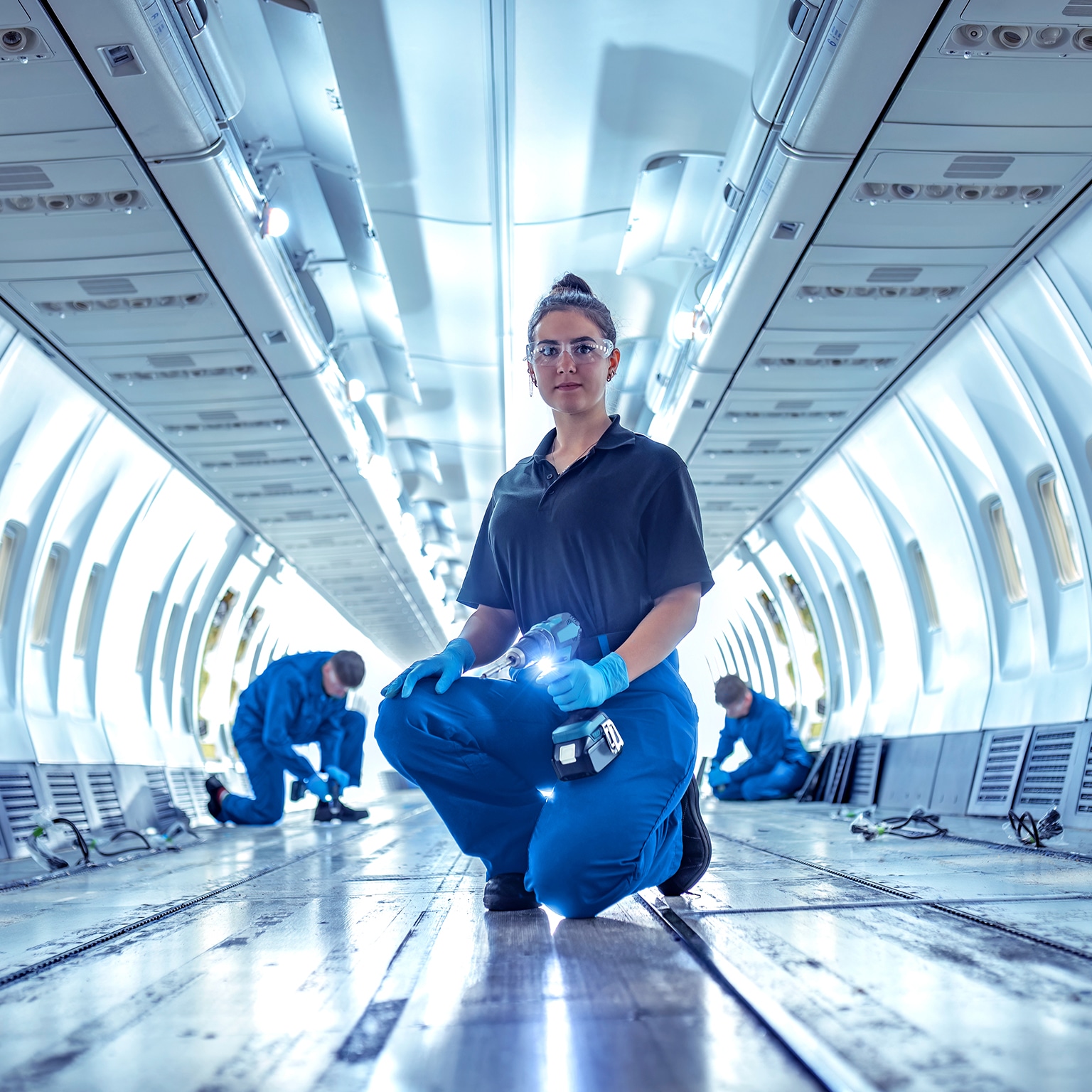 Portrait of female apprentice aircraft maintenance engineer in empty jet - stock photo