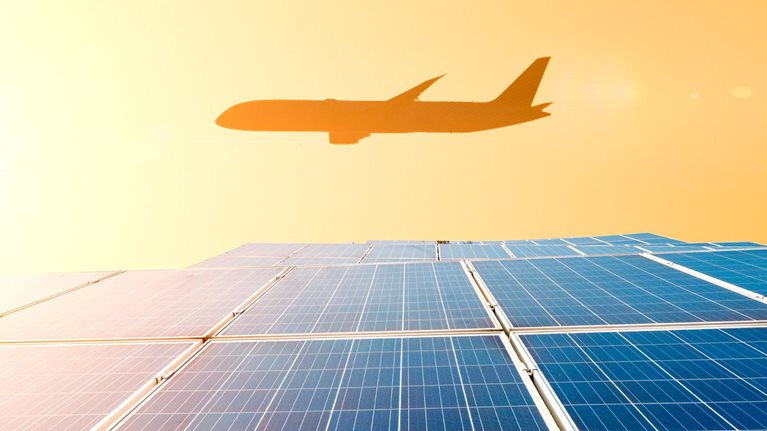 Airplane flying over the solar panel plant in a sunny day