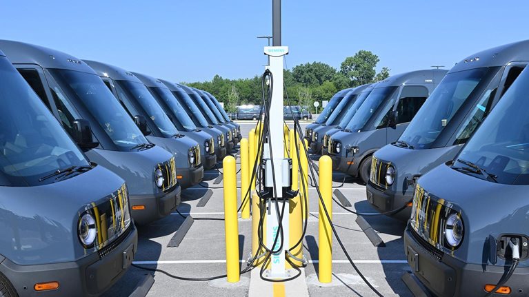 Rivian trucks, facing each other, plugged in and charging. - stock photo