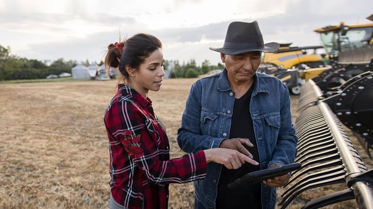 Farmer couple with digital tablet at combine harvester on farm - stock photo