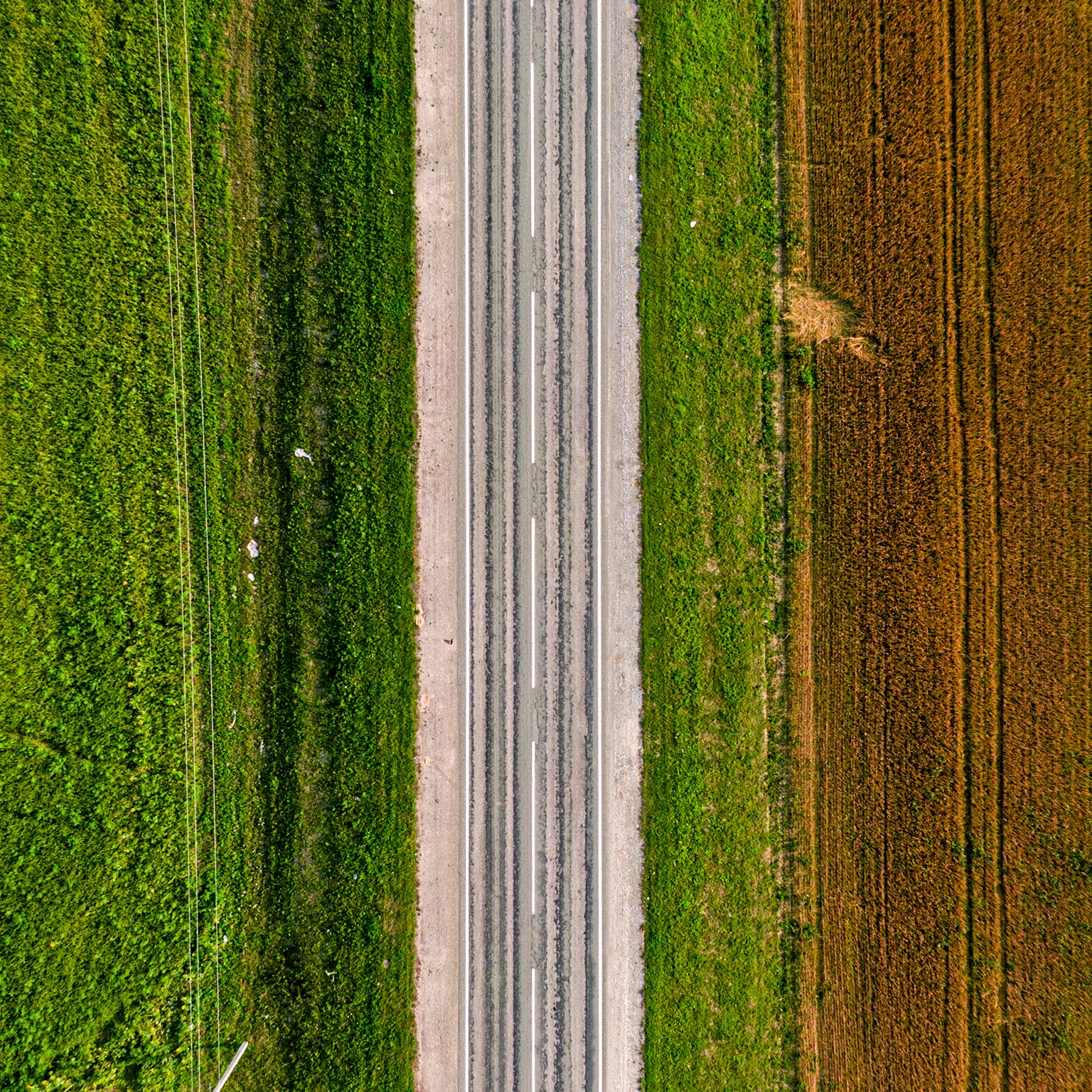Aerial shot of an empty highway on a green and brownfield