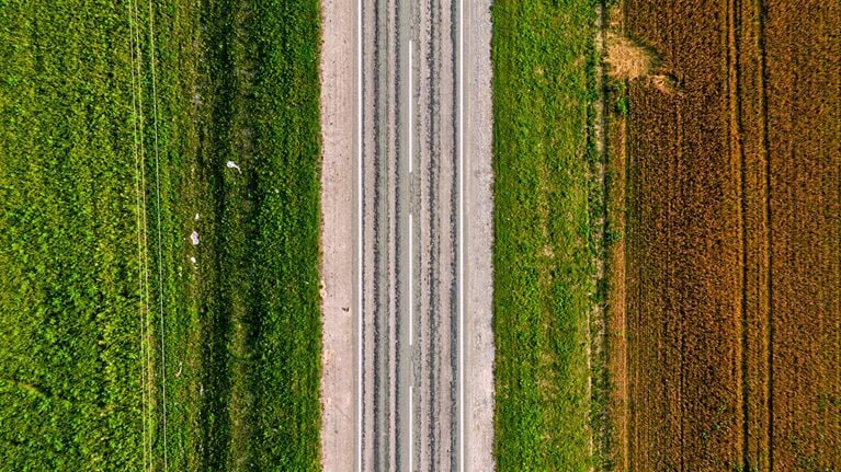 Aerial shot of an empty highway on a green and brownfield
