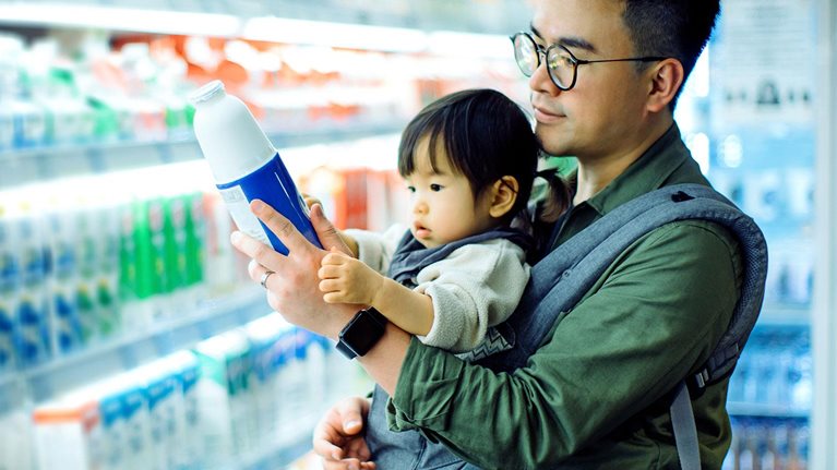 Young Asian father with daughter grocery shopping for dairy products in supermarket