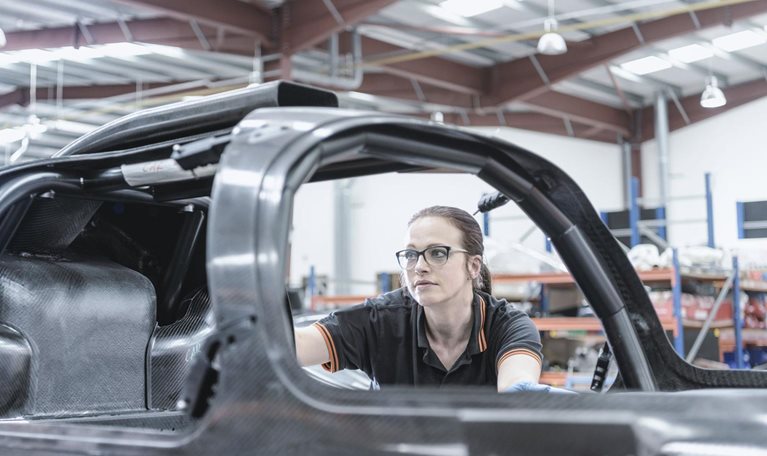 Female engineer inspecting carbon fiber body in racing car factory