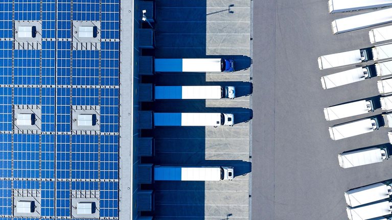 Aerial view of trucks loading at distribution warehouse with solar photovoltaic panels