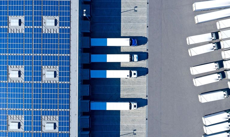 Aerial view of trucks loading at distribution warehouse with solar photovoltaic panels