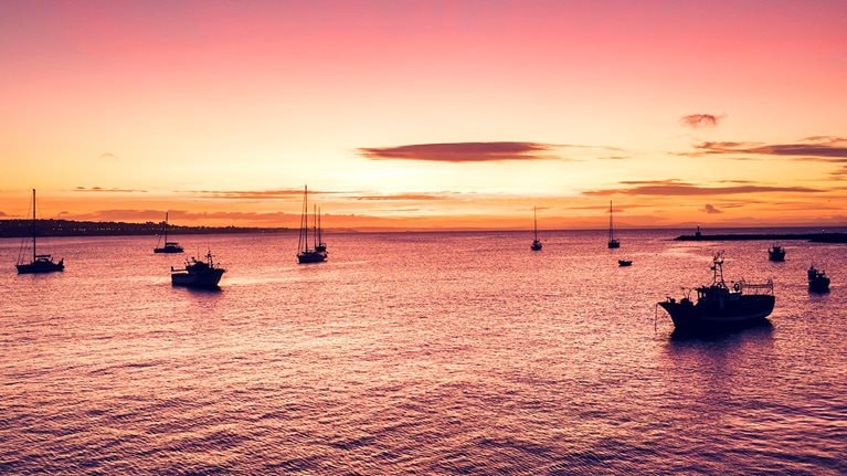 Aerial view of boats and ships in the sea near the port in Cascais, Portugal during sunset