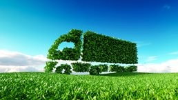 3D rendering of green green truck icon on fresh spring meadow with blue sky in background.