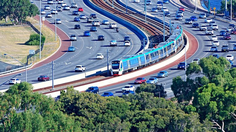 City transport: electric train travels down middle of busy freeway