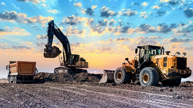 Excavators working on construction site at sunset