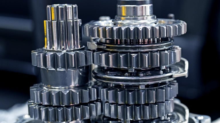 A close-up of a cluster of silver gears arranged in a complex mechanical assembly.