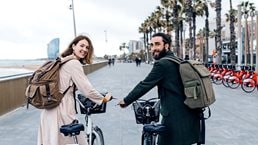 Smiling couple with e-bikes on beach promenade
