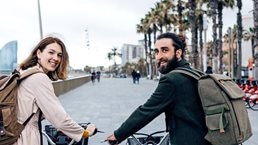 Smiling couple with e-bikes on beach promenade
