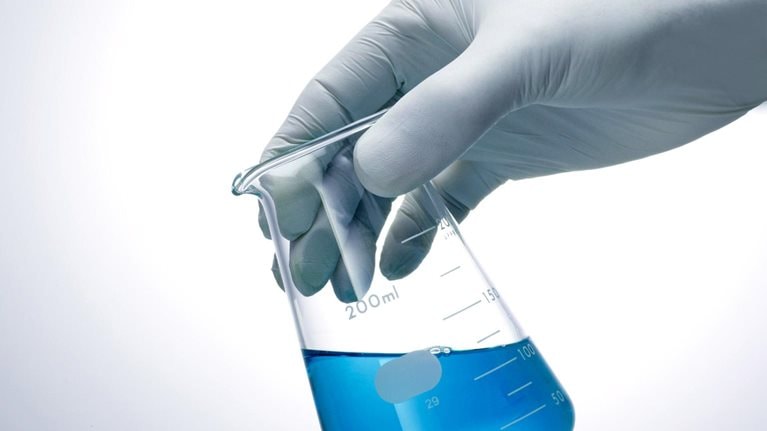 Hand holding a blue liquid flask