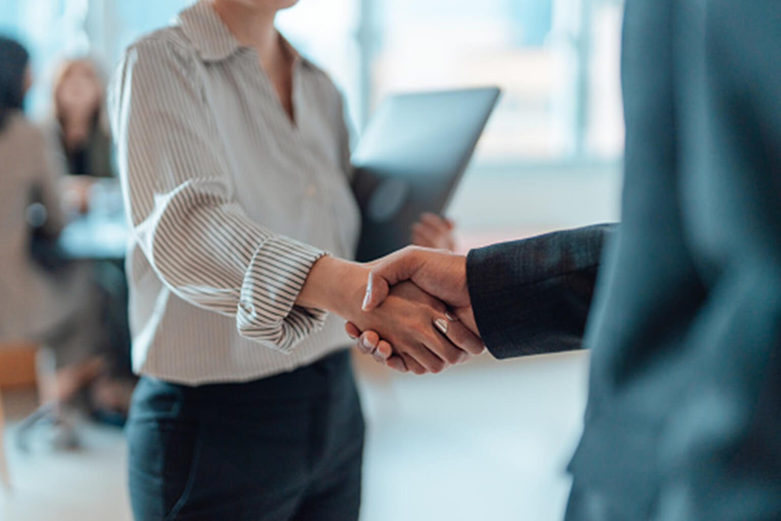 This image depicts a professional business setting where individuals are shaking hands, commonly symbolizing a finalized agreement, a successful negotiation, or a friendly introduction.