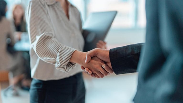 This image depicts a professional business setting where individuals are shaking hands, commonly symbolizing a finalized agreement, a successful negotiation, or a friendly introduction.
