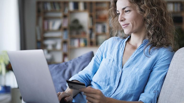 Smiling woman doing online shopping on laptop at home 
