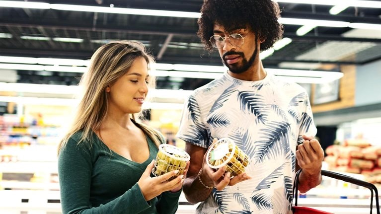 Young couple shopping and discussing purchase decision in grocery store.