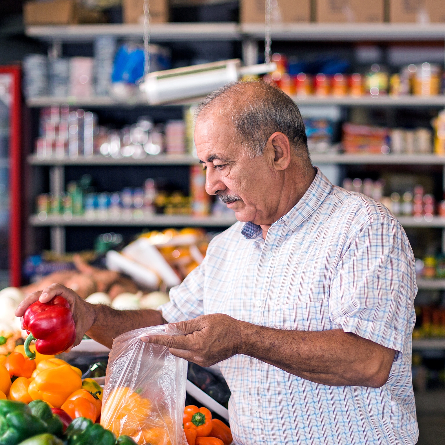 Handsome older man buying peppers at the supermarket