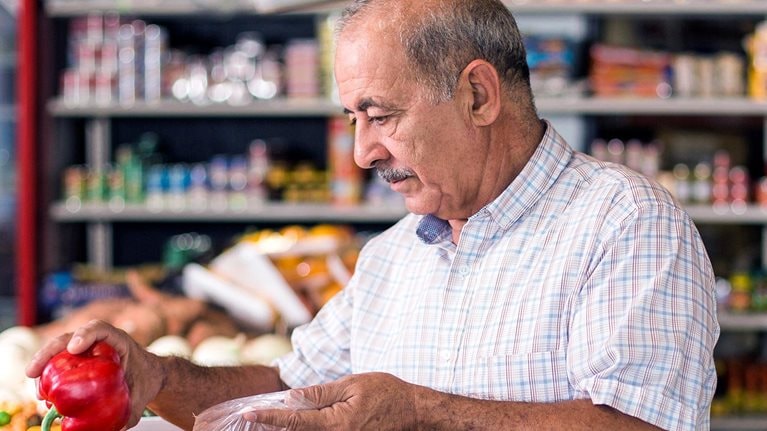 Handsome older man buying peppers at the supermarket