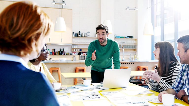 A team meeting at which five colleagues are reviewing creative ideas.