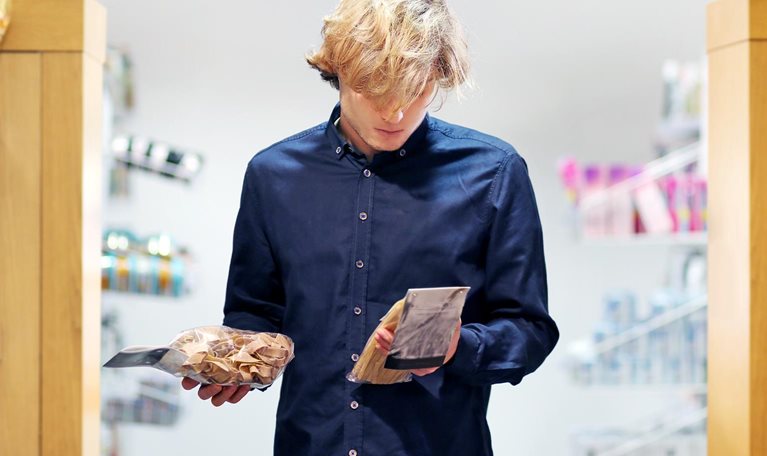 Teenager shopping in supermarket, reading product information