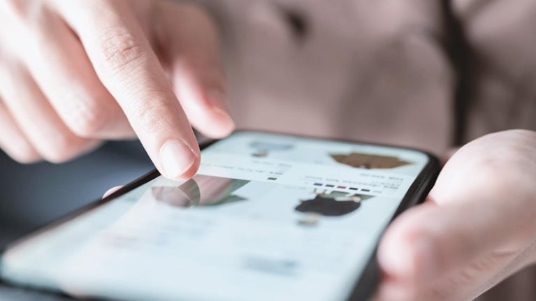 Woman online shopping on smart phone fashion clothes at home