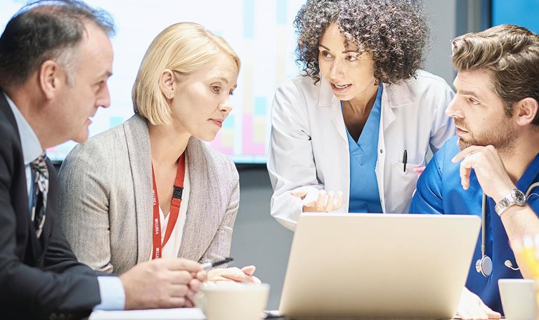 a mixed group of healthcare professional and business people meet around a conference table