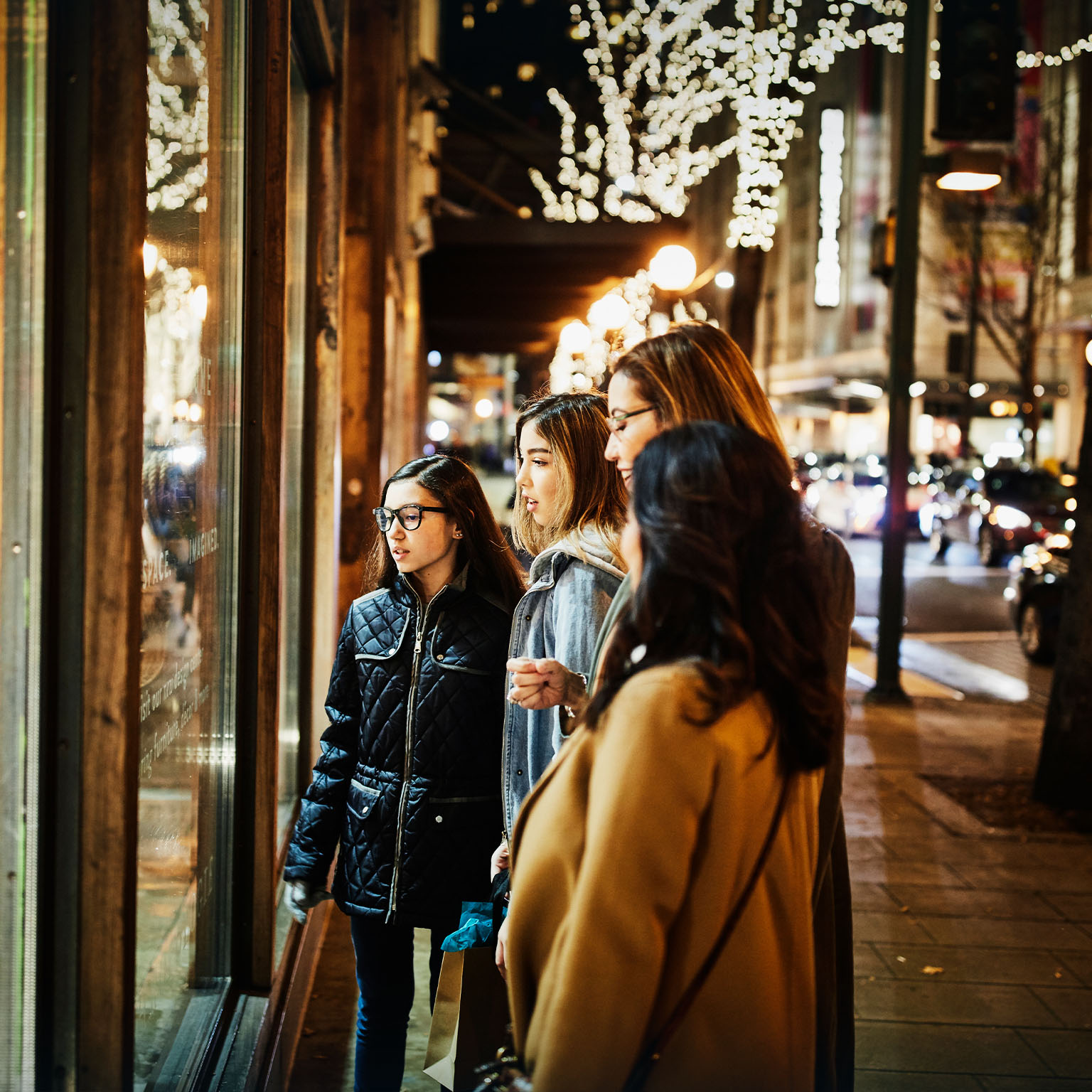 Two mature women and teenage daughters window shopping during holidays