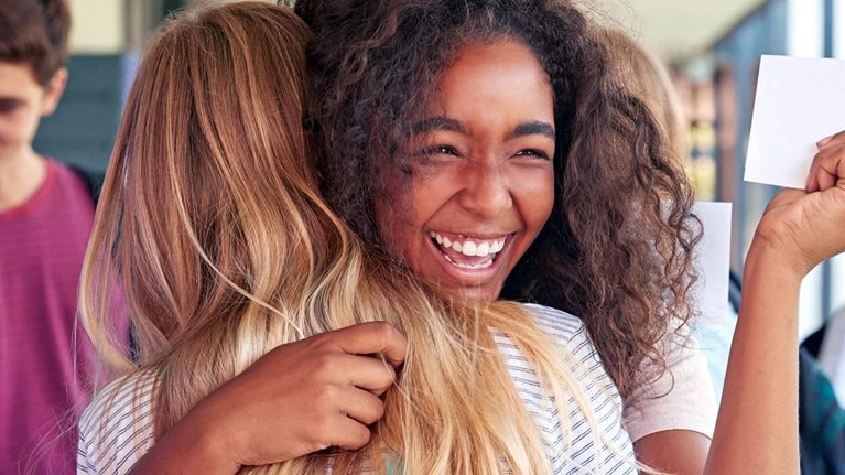 Two girls celebrating exam results in school corridor