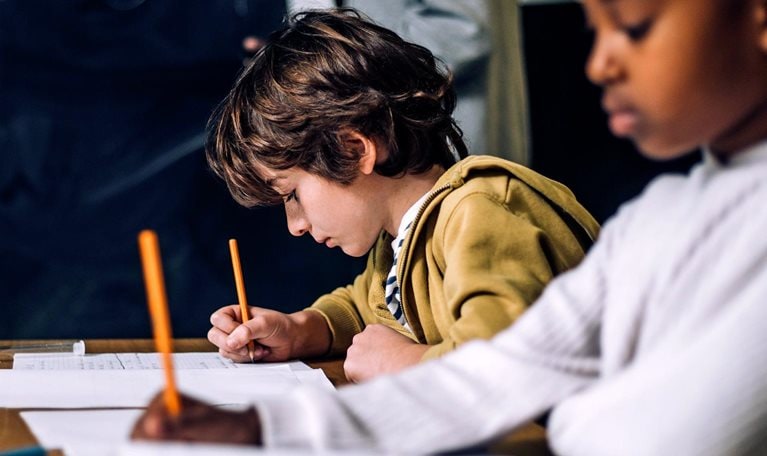 Smiling boy talking to female student while sitting in classroom