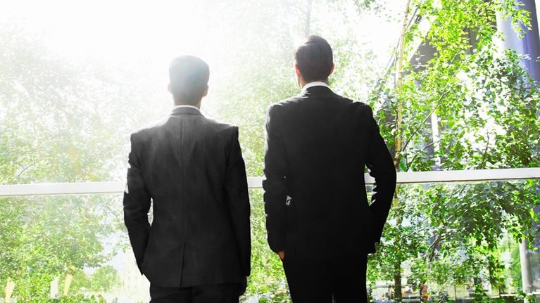 Two businessmen surrounded by trees. - stock photo