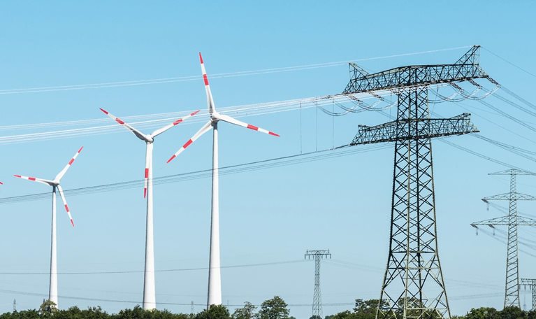 Grassy landscape with wind turbines, power lines, and solar panels.