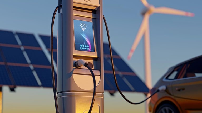 Electric car charging with wind turbines and solar panel - stock photo