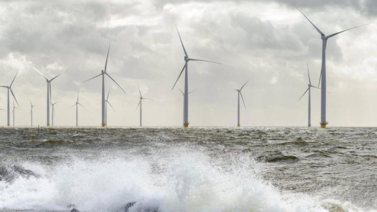 Offshore wind turbines during a storm as waves crash against rocks